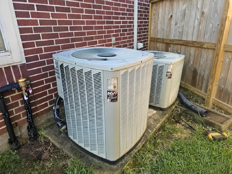 Two outdoor units installed side by side along a fence line
